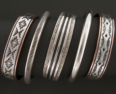 An image of a five silver and copper bracelets.